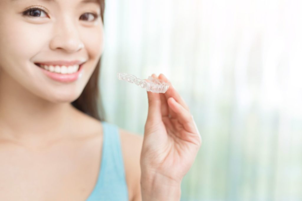 Invisalign Mobile AL | Clear Aligner Treatment – Pickett Orthodontics Woman holding Invisalign clear aligner – Invisalign treatment in Mobile, AL at Pickett Orthodontics