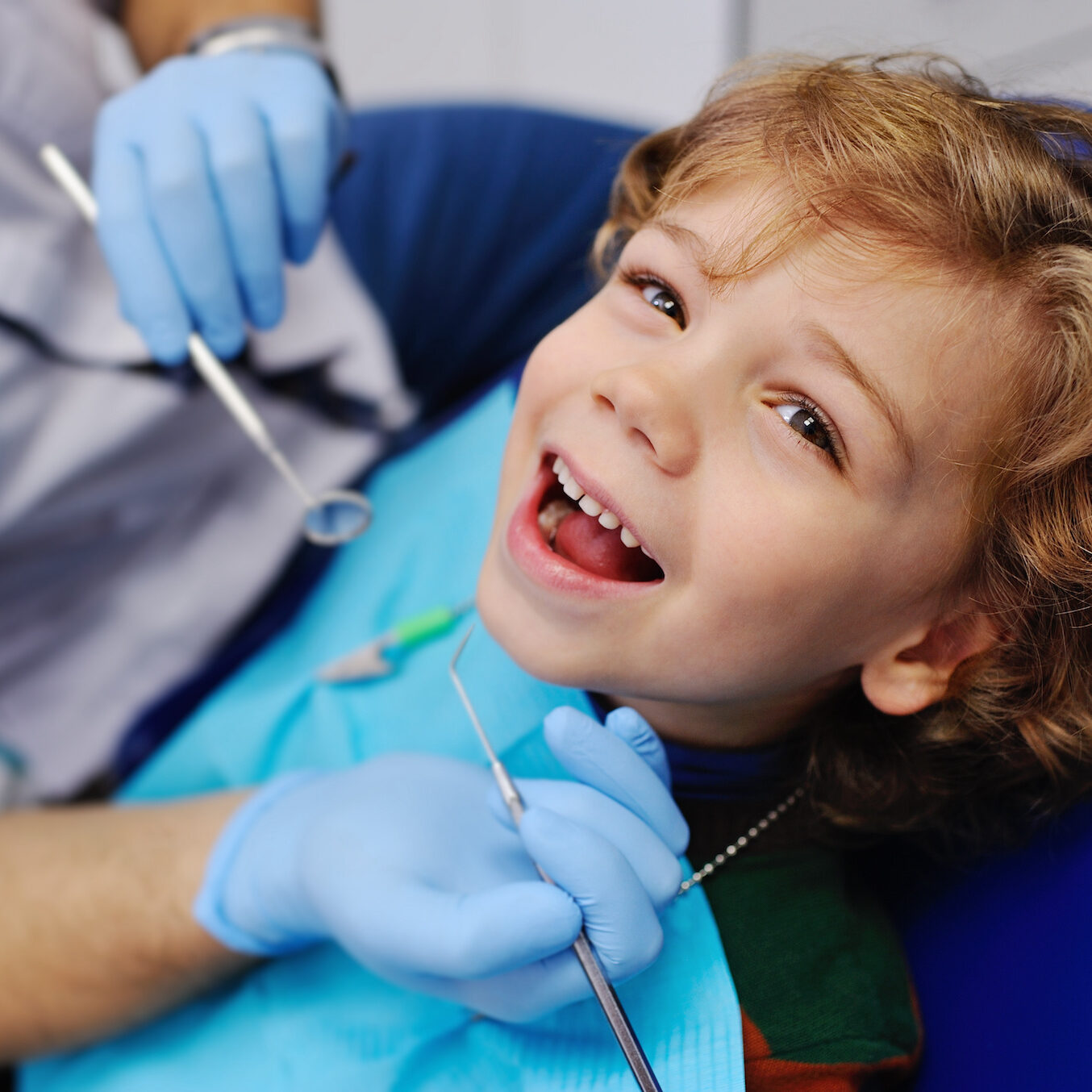 smiling child sitting in a blue chair dental