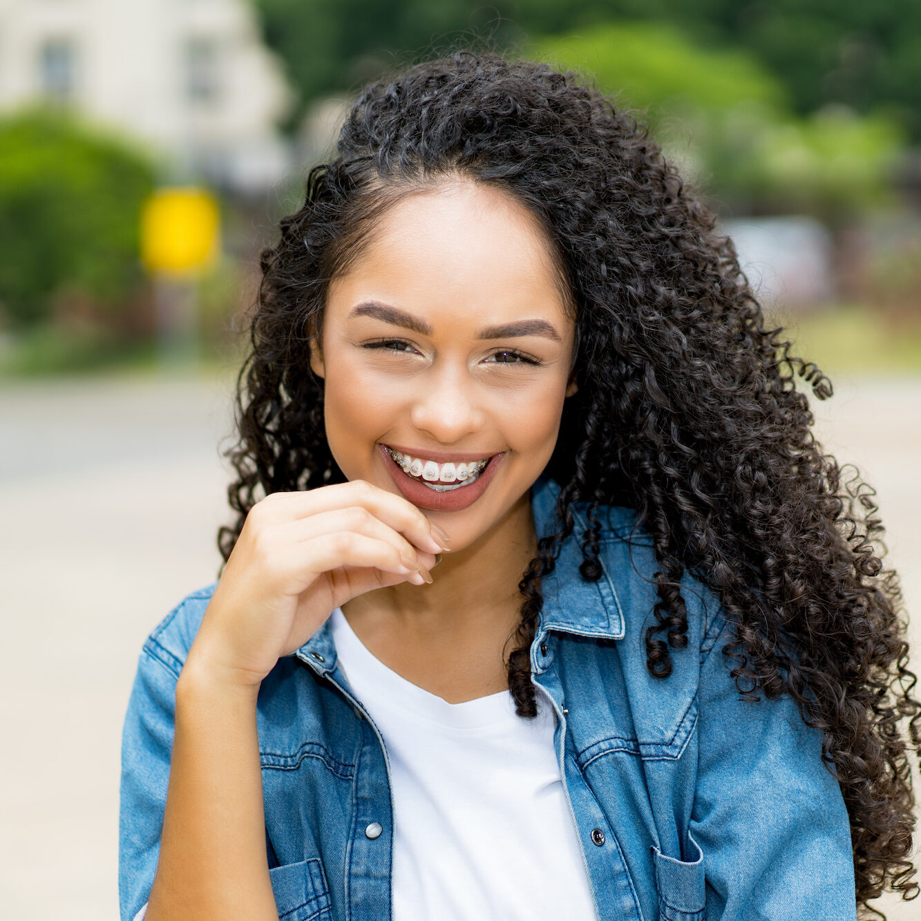 Pretty brazilian young adult woman with retainer outdoor in summer in city